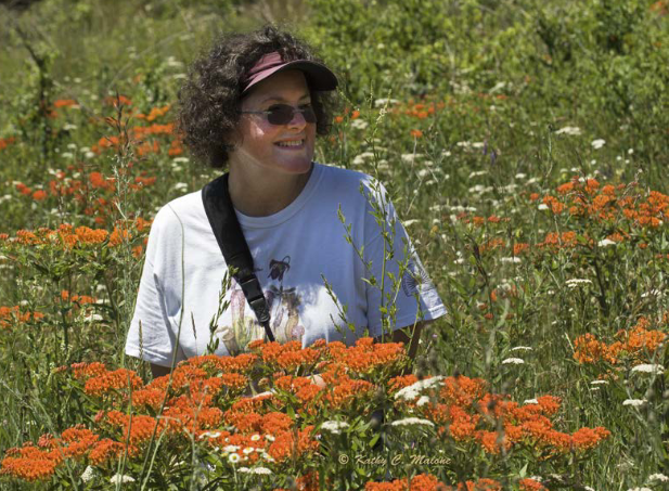 Picture of Barbara Woodmansee standing in a field of wildflowers