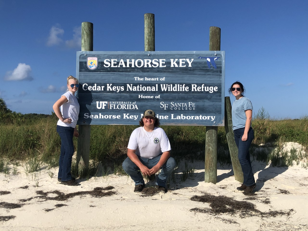 Youth Conservation Corps 2021 taking a work breaking to pose at sign on Seahorse Key.